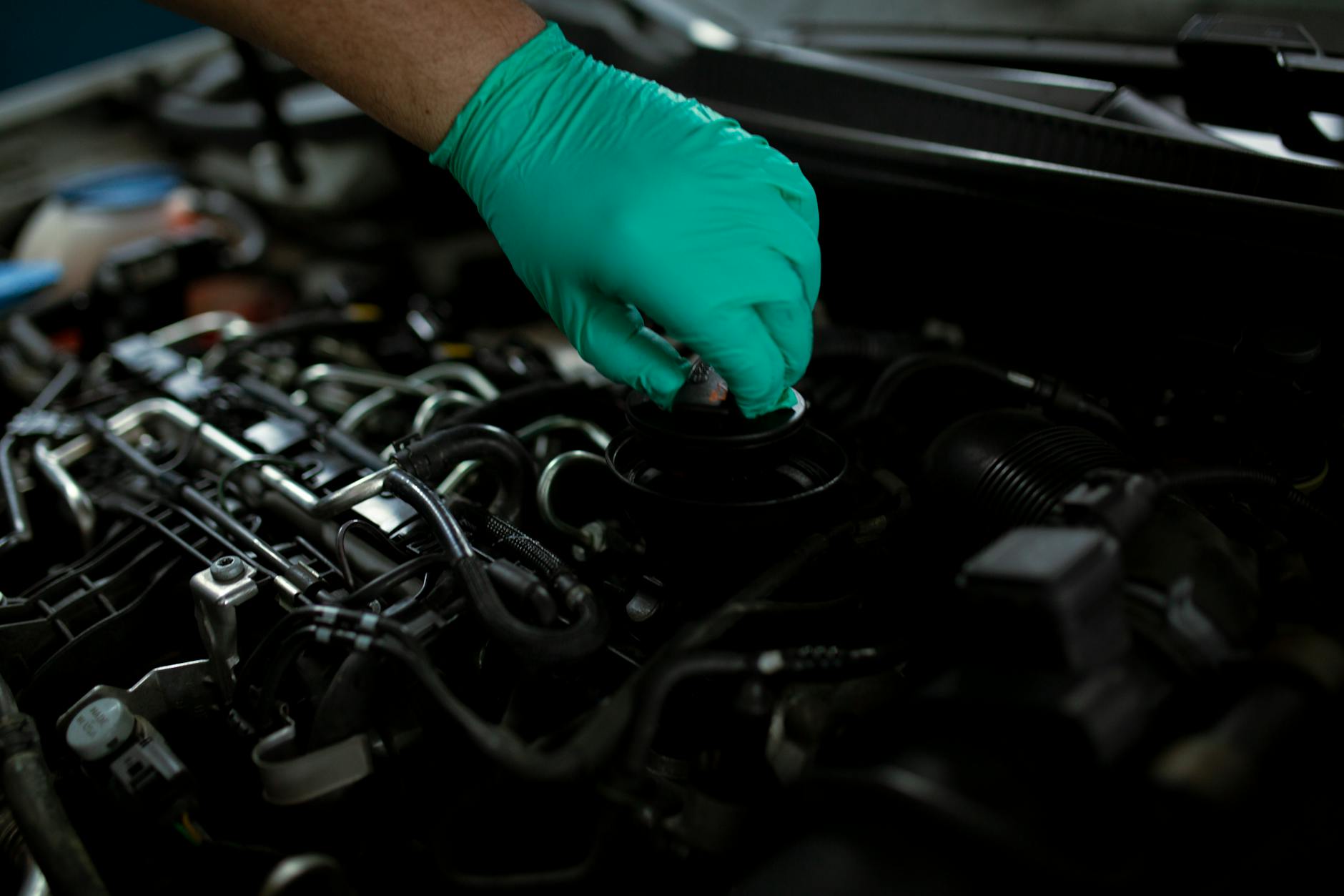 a mechanic opening the oil filler cap of a car engine
